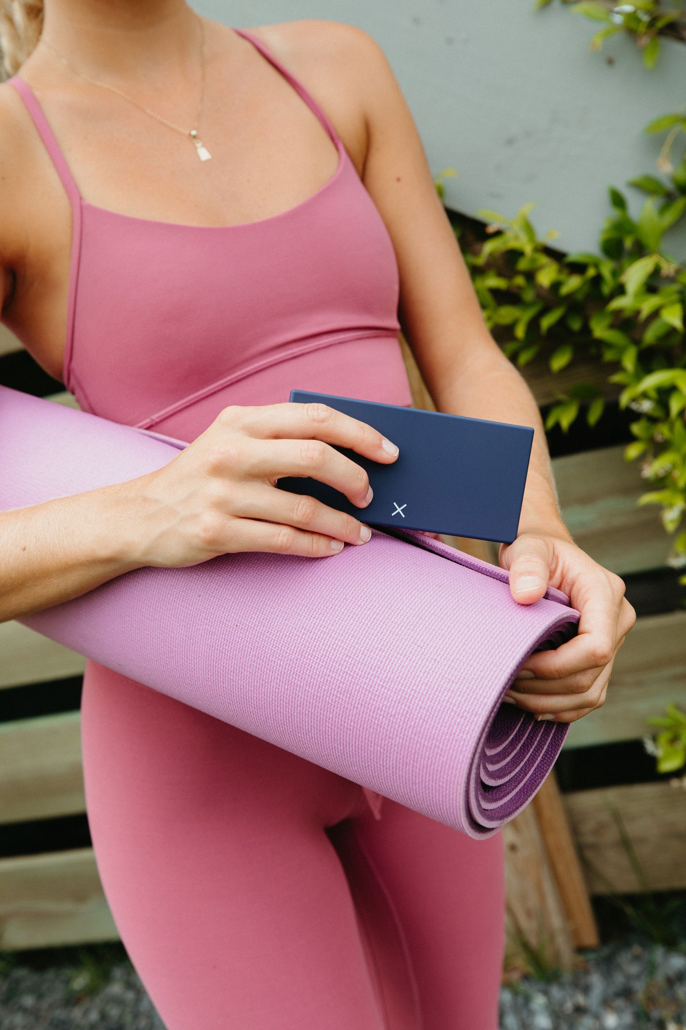 Cute blue Port and Polish pill box being held by a woman wearing pink yoga clothes and carrying a pink yoga mat